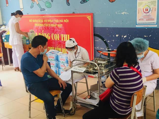 Các bác sĩ, điều dưỡng của Bệnh viện Mắt Hồng Sơn hỗ trợ tiêm chủng cho người dân ở Trạm y tế phường Giáp Bát